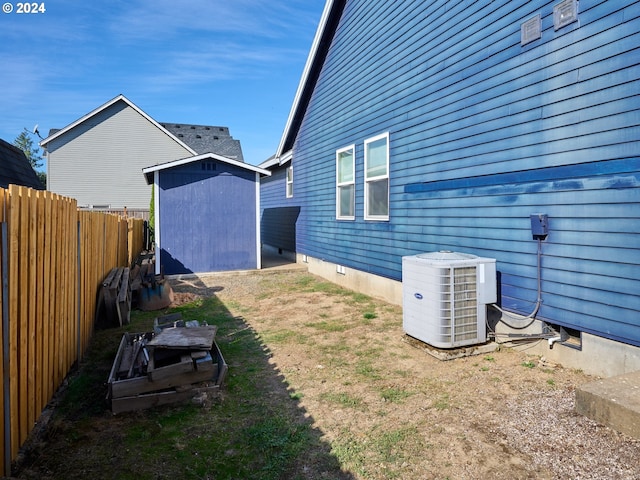 view of yard featuring a storage shed, an outdoor structure, cooling unit, and fence