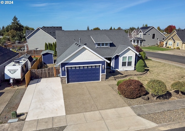 view of front of house with a garage, concrete driveway, stone siding, a residential view, and fence