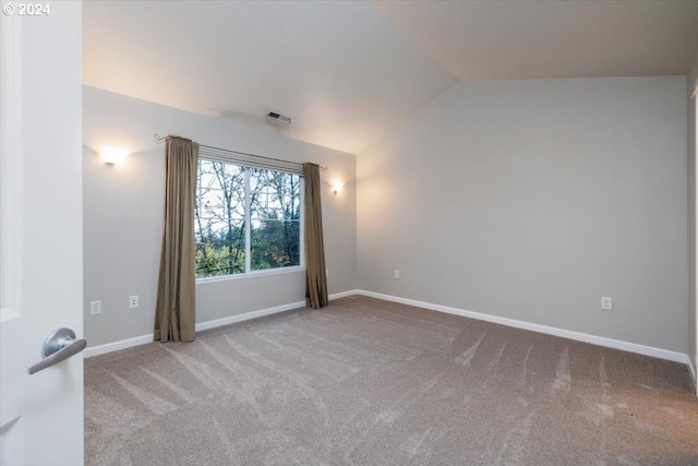 carpeted spare room featuring vaulted ceiling