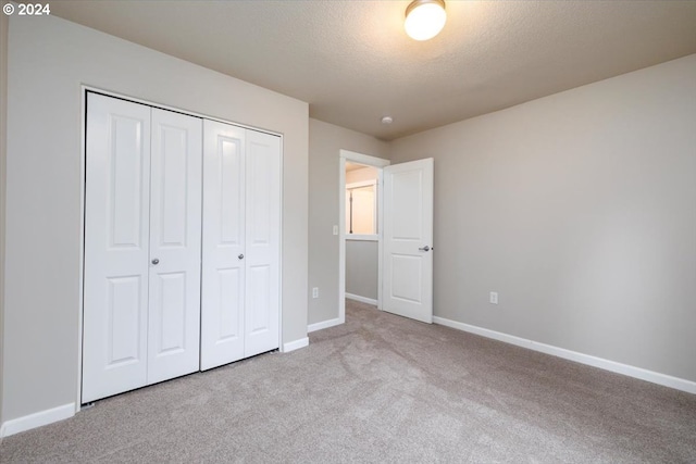 unfurnished bedroom featuring light carpet, a textured ceiling, and a closet