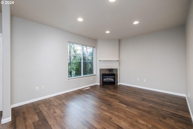 unfurnished living room featuring dark hardwood / wood-style flooring and a tiled fireplace