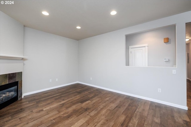 unfurnished living room featuring a tile fireplace and dark hardwood / wood-style floors