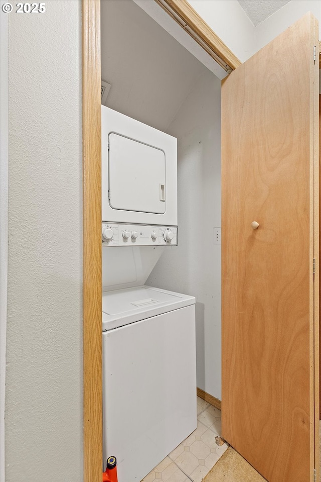 clothes washing area featuring stacked washer and dryer and light tile patterned floors