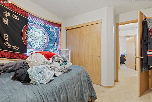 bedroom featuring light carpet, a closet, and a textured ceiling