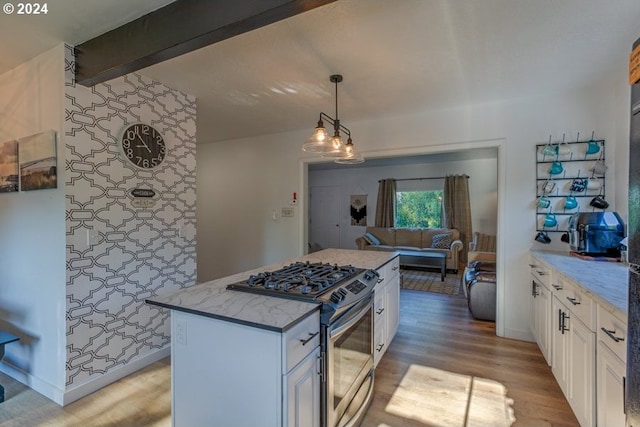 kitchen featuring gas stove, light wood-type flooring, a kitchen island, white cabinetry, and open floor plan