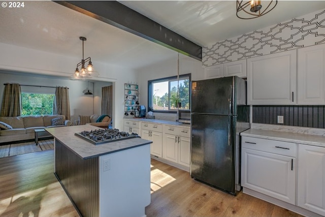 kitchen featuring light wood-type flooring, gas cooktop, white cabinets, and freestanding refrigerator