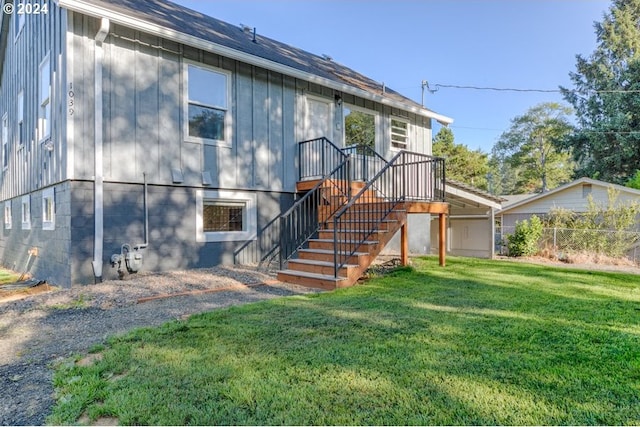 rear view of house with stairs, a yard, and fence