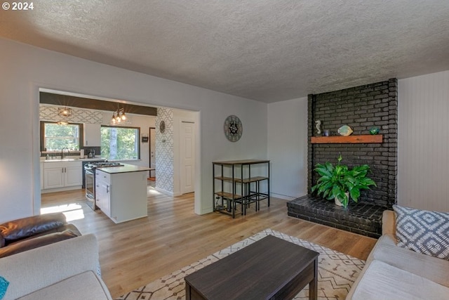 living area featuring light wood-style flooring, a fireplace, and a textured ceiling