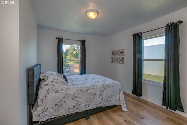 bedroom with a textured ceiling and wood finished floors