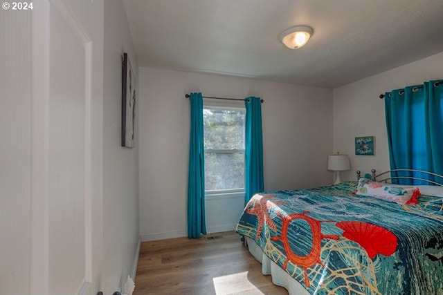 bedroom featuring visible vents, baseboards, and wood finished floors