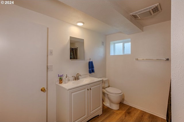 bathroom featuring visible vents, toilet, vanity, and wood finished floors