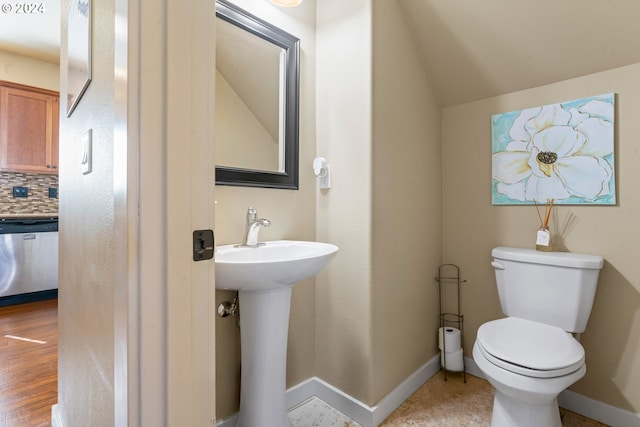 bathroom with toilet, sink, wood-type flooring, backsplash, and vaulted ceiling