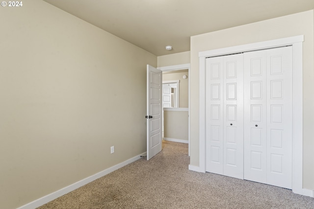 unfurnished bedroom featuring a closet and light colored carpet