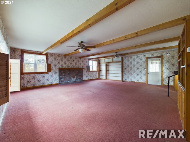 unfurnished living room with beam ceiling, a healthy amount of sunlight, carpet flooring, and wallpapered walls