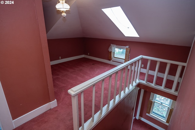 stairs with vaulted ceiling with skylight, carpet flooring, plenty of natural light, and baseboards