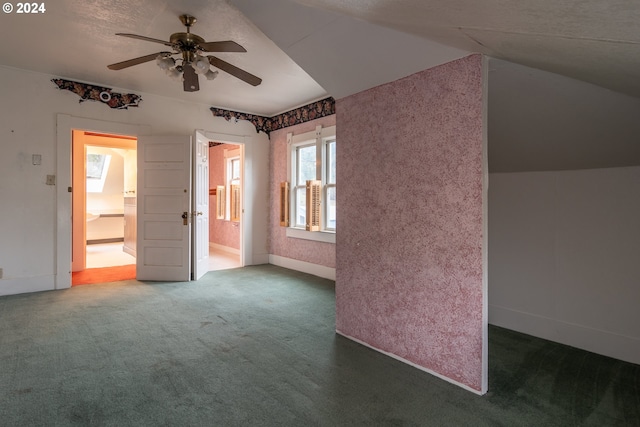 interior space featuring lofted ceiling, baseboards, dark carpet, and a ceiling fan