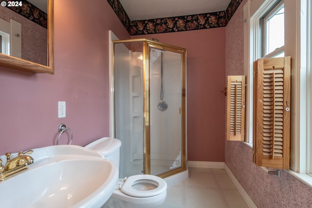 full bathroom featuring toilet, a stall shower, baseboards, and a sink