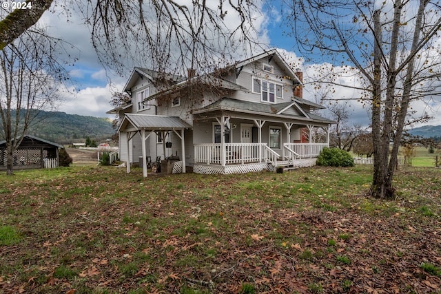 view of front facade with a front lawn, a mountain view, and a porch