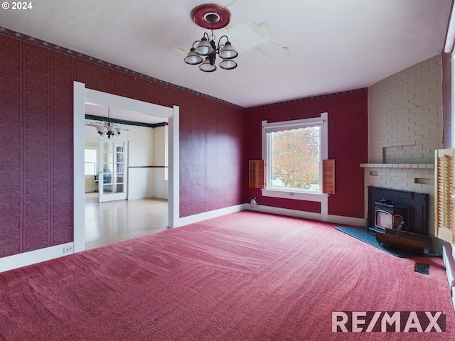 unfurnished living room with an inviting chandelier, carpet, baseboards, and wallpapered walls