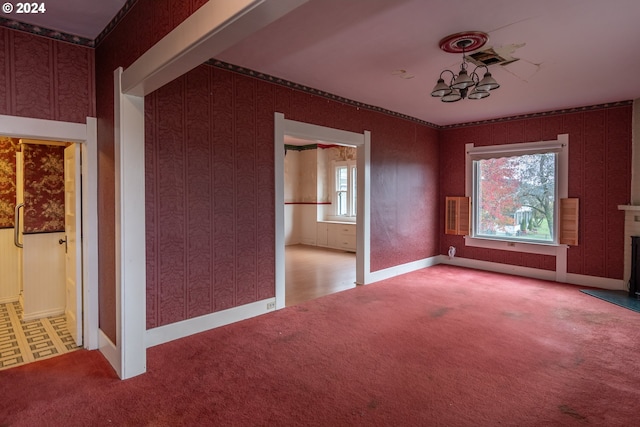 carpeted spare room featuring wallpapered walls, visible vents, baseboards, a fireplace, and a chandelier