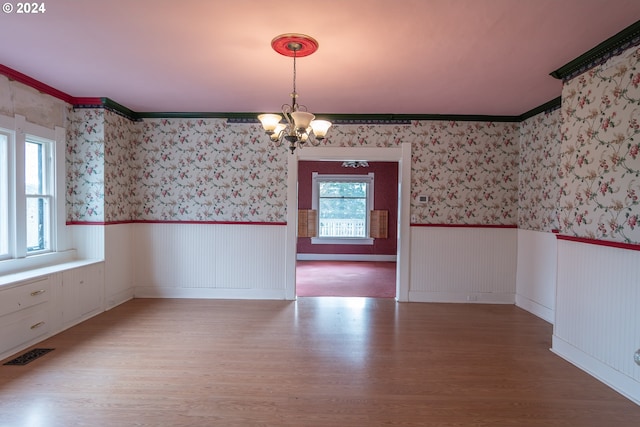 unfurnished dining area featuring a wainscoted wall, a healthy amount of sunlight, visible vents, and wallpapered walls