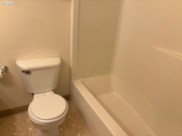 bathroom with tile patterned flooring, toilet, and plus walk in shower