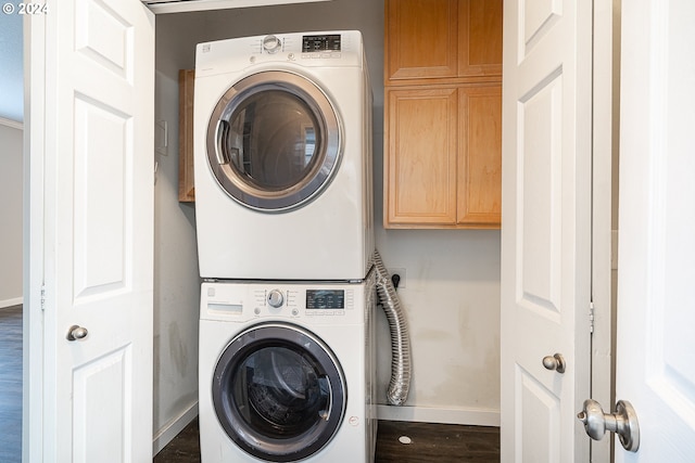 washroom with cabinets, dark hardwood / wood-style flooring, and stacked washer / dryer