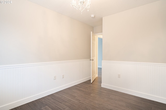 spare room with dark wood-type flooring and an inviting chandelier