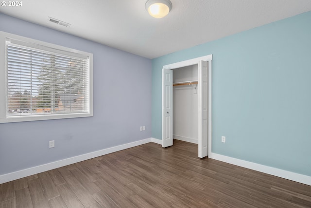 unfurnished bedroom featuring dark wood-type flooring and a closet