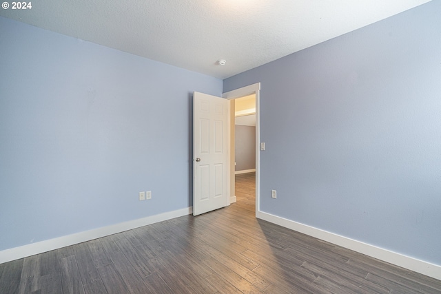 empty room featuring dark hardwood / wood-style floors and a textured ceiling