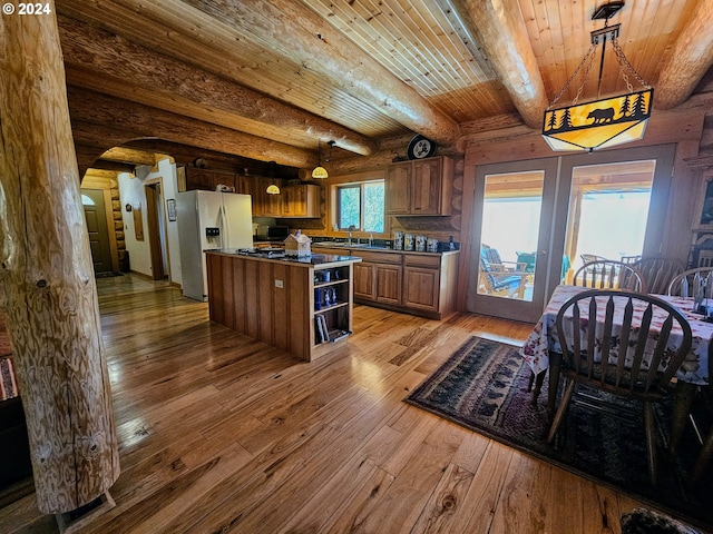 kitchen with beamed ceiling, stainless steel refrigerator with ice dispenser, decorative light fixtures, and hardwood / wood-style flooring