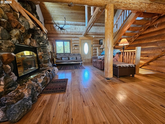 unfurnished living room featuring log walls, a fireplace, wood-type flooring, and high vaulted ceiling