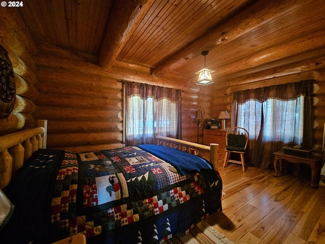 bedroom featuring beamed ceiling, multiple windows, rustic walls, and hardwood / wood-style floors