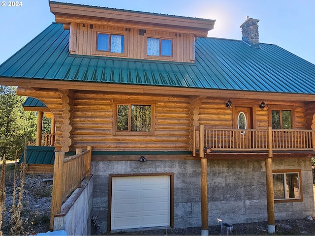 log home featuring log exterior, an attached garage, a chimney, and metal roof