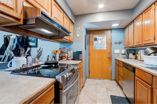 kitchen with tasteful backsplash, light tile patterned flooring, sink, stainless steel appliances, and extractor fan