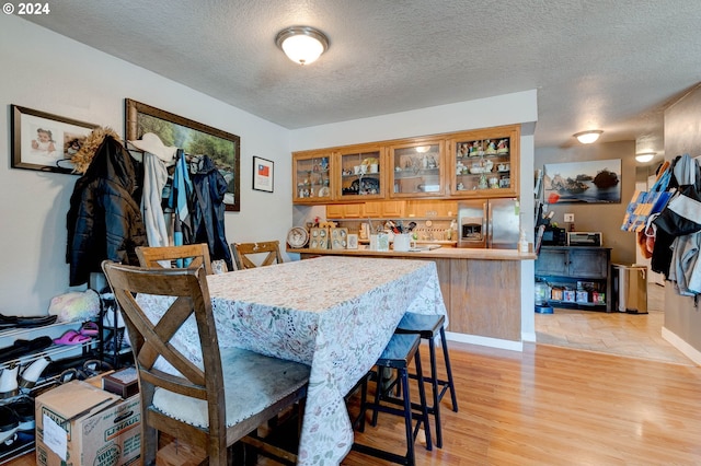 dining area with light wood-type flooring and a textured ceiling