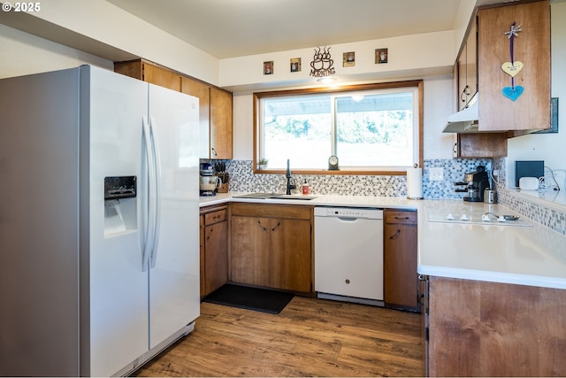 kitchen with decorative backsplash, sink, wood-type flooring, and white appliances