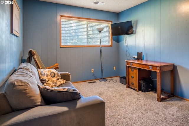 home office with a textured ceiling, light colored carpet, and wood walls