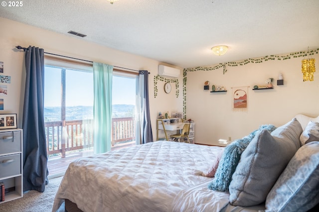 bedroom featuring carpet flooring, a textured ceiling, access to outside, and an AC wall unit