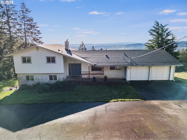 tri-level home with a mountain view, a garage, and a front yard