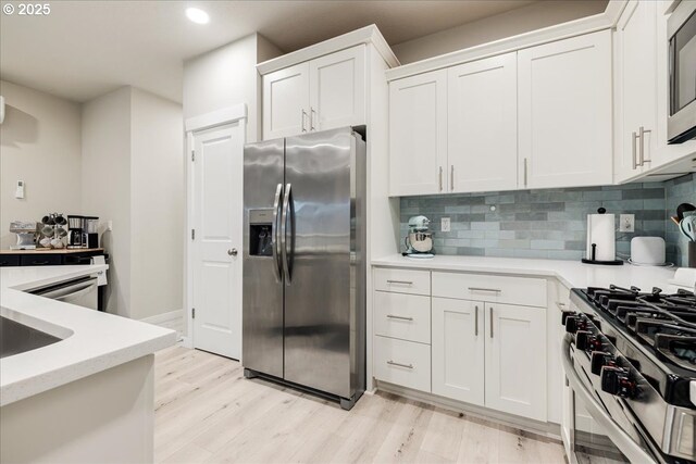 kitchen with appliances with stainless steel finishes, light countertops, white cabinets, and decorative backsplash