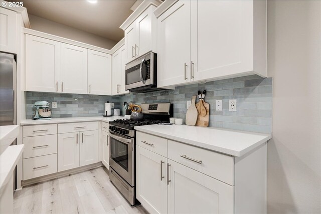 kitchen with white cabinetry, appliances with stainless steel finishes, light countertops, and backsplash