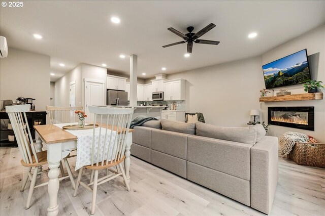 living room with light wood-type flooring, a glass covered fireplace, and recessed lighting