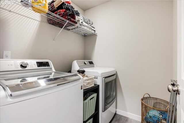 clothes washing area with laundry area, baseboards, separate washer and dryer, and wood finished floors