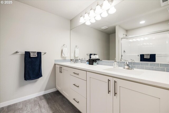 full bathroom featuring double vanity, a sink, baseboards, and wood finished floors