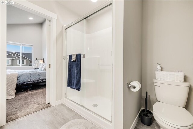 full bathroom with a stall shower, baseboards, toilet, and ensuite bath