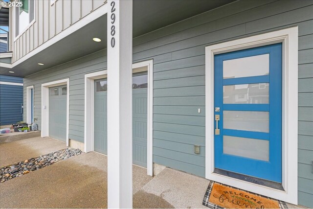 doorway to property featuring board and batten siding, a balcony, and a garage