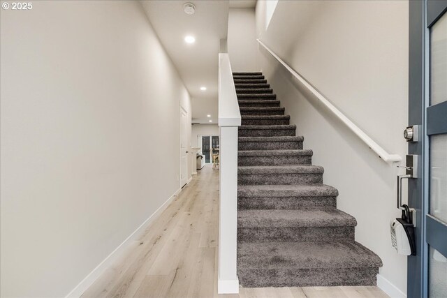 stairs featuring baseboards, wood finished floors, and recessed lighting