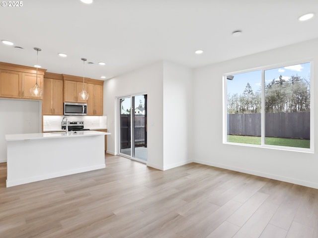 1923 NW 18th Ave, Battle Ground, WA 98604 - kitchen with appliances with stainless steel finishes, light hardwood / wood-style floors, hanging light fixtures, and a center island with sink