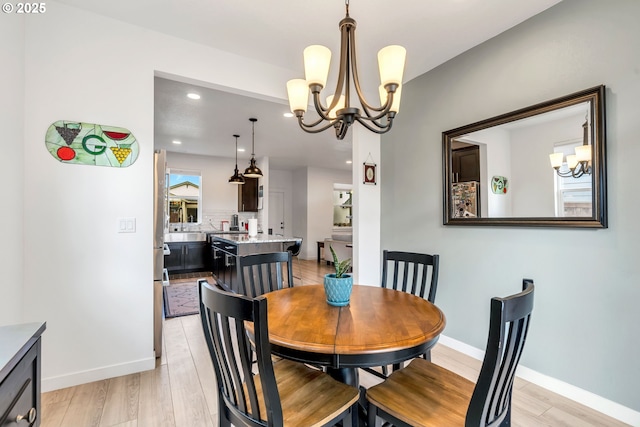 dining area featuring light wood-style flooring, baseboards, and an inviting chandelier